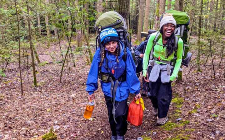 two girls smile as they backpack on an outward bound course